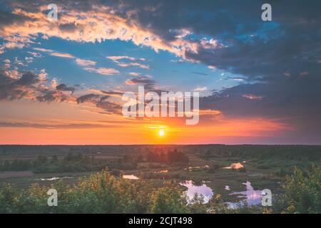 Schöne Erstaunliche Sonnenaufgang Über Sommerwald Und Flusslandschaft. Szenischer Blick Auf Den Morgenhimmel Mit Aufgehender Sonne Über Dem Wald. Frühsommer Natur Von Stockfoto