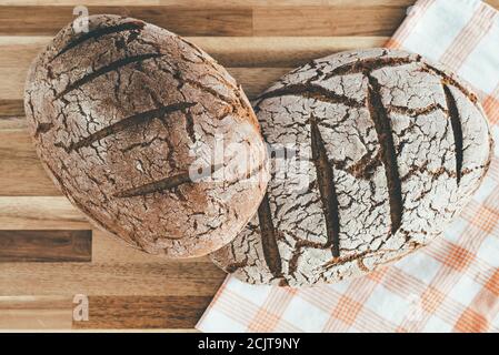 Direkt über Ansicht von zwei Laibe reinen Roggensauerteigs Brot auf Holzoberfläche Stockfoto