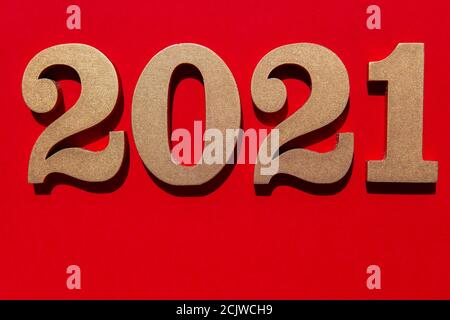 Neujahr rot Hintergrund mit glänzenden goldenen Zahlen 2021. Minimalistisches Konzept auf rotem Papier mit harten Schatten. Stockfoto