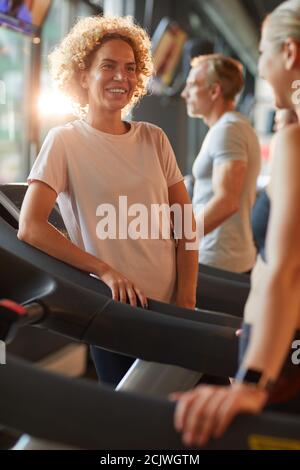 Glückliche schöne Frau im Gespräch mit ihrem Freund während ihres Sports Training im Fitnessstudio Stockfoto