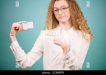 Nahaufnahme abgeschnitten Foto von jungen schlanken blonde Frau tragen Brille schiebt auf Visitenkarte auf dem isolierten blauen Hintergrund Stockfoto