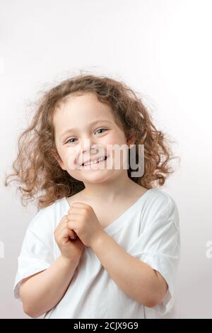 Lächelnd schönes Mädchen mit langen, welligen Haaren Blick auf die Kamera. Glück Konzept.Happy Kindheit Stockfoto