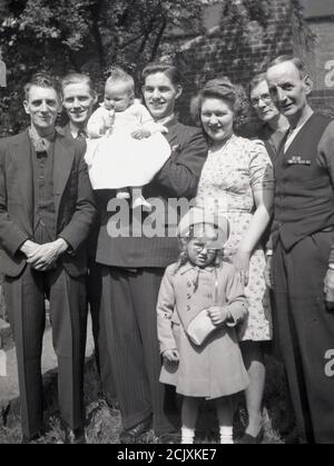 1950er Jahre, historisches Bild zeigt die Kleidung und Mode der Zeit als Familie stehen zusammen für ein Gruppenfoto, mit einem stolzen jungen Vater hält sein Kleinkind, England, Großbritannien. Stockfoto