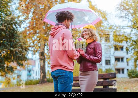 Schwarzer Mann Blumen zu seinen Kaukasischen Freundin im Herbst Stockfoto