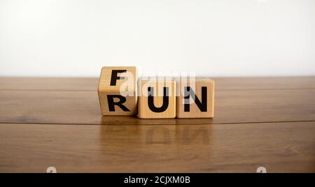 Hand dreht einen Würfel und ändert das Wort Fun to Run. Schöner Holztisch, weißer Hintergrund. Lifestyle-Konzept, Kopierraum. Stockfoto