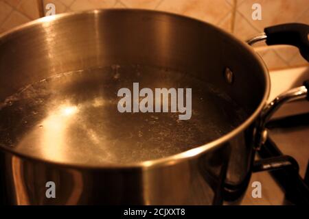 Pfanne auf der heimischen Küche mit Herd, auf dem Wasser kocht Im echten Leben Stockfoto