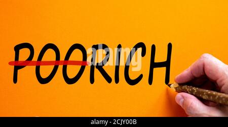 Hand mit schwarzem Bleistift Schrift "arm reich", isoliert auf schönen orangen Hintergrund. Geschäftskonzept, Kopierbereich. Stockfoto