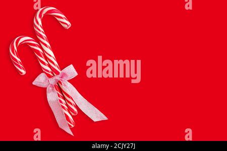 Weihnachten Süßigkeiten Stöcke mit Band isoliert auf rotem Hintergrund mit Clipping Pfad. Stockfoto