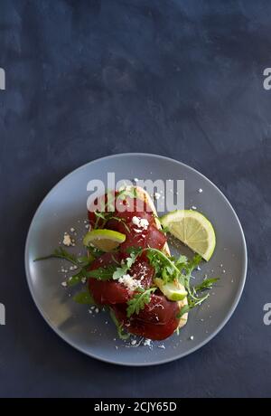 Brotscheibe mit Bresaola, Rucola und Parmesan. Konzept der gesunden Ernährung. Blick von oben. Stockfoto