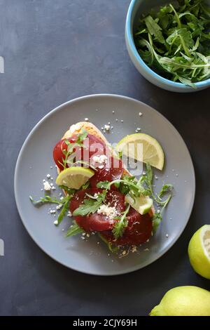 Brotscheibe mit Bresaola, Rucola und Parmesan. Konzept der gesunden Ernährung. Blick von oben. Stockfoto