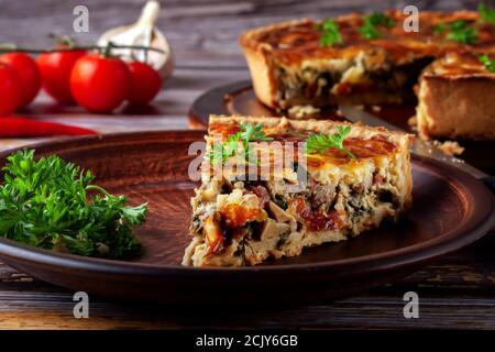 Französische Quiche mit Huhn und Pilzen auf Holzgrund Stockfoto