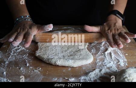 Hausgemachten Teig zubereiten. Frau Hände Kneten frischen Teig für Brot oder Pizza auf einem bemehlten Tisch. Stockfoto