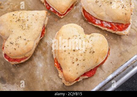 Herzförmige Pizzateig-Sandwiches mit Tomate, Mozzarella und Basilikum, Blick in den hohen Winkel Stockfoto