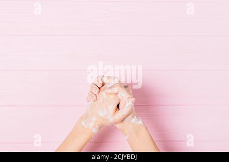 Frau, die sich die Hände mit Seife wäscht, Nahaufnahme auf rosa Hintergrund, Draufsicht. Stockfoto