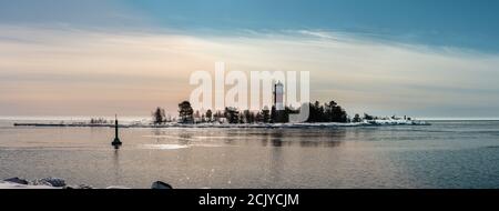 Panorama des rot-weißen Leuchtturms in der Mitte des gefrorenen, mit Schneeinsel an der kalten Ostsee bedeckt, teilweise offenes Wasser, dünnes Eis reflektierendes Tageslicht. B Stockfoto