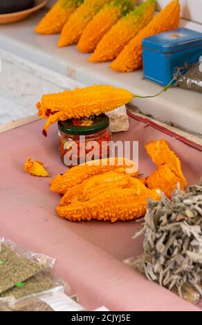 Sehr reife dunkelgelbe Balsam Birne Früchte an einer Straßentheke, Verkauf von Bio-Zutaten. Rote Samen werden in einem Glasgefäß gesammelt Stockfoto