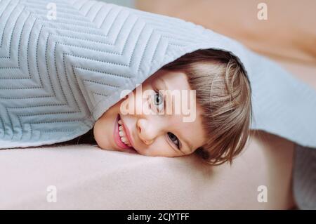 Happy schönes kleines Mädchen mit Spaß Zeit auf dem Bett unter der Decke im Schlafzimmer liegen. Stockfoto