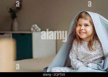 Happy schönes kleines Mädchen mit Spaß Zeit auf dem Bett unter der Decke im Schlafzimmer liegen. Stockfoto