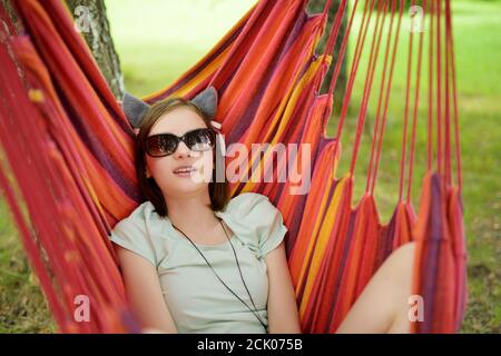 Happy junge Mädchen in der Hängematte am schönen Sommertag entspannen. Nettes Kind, das Spaß im Sommerpark hat. Familienurlaub im Sommer. Stockfoto