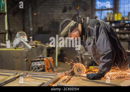 Professionelle schmied Sägen von Metall mit der Kreissäge in der Schmiede, Werkstatt. Handarbeit, Handwerk und Schmiedekunst Konzept Stockfoto