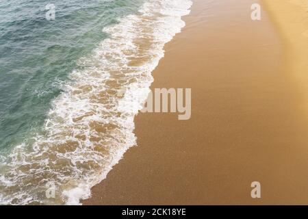 Von einem Pier aus hat man einen Blick auf die Wellen, die auf den Sandstrand schwassen. Stockfoto