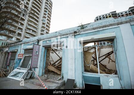 Baku Aserbaidschan - 2. Mai 2019: Seitenansicht des blauen verlassenen zerstörten alten Gebäudes im Zentrum von Baku, Azierbaijan mit hoher Bauwohnung Stockfoto