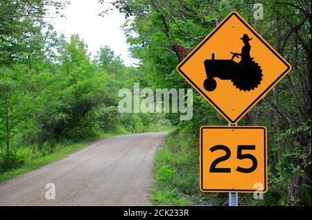 Gelbe Traktorüberquerung und Geschwindigkeitsbegrenzung durch ein Land Straße in der Nähe Londonderry.Vermont.USA Stockfoto