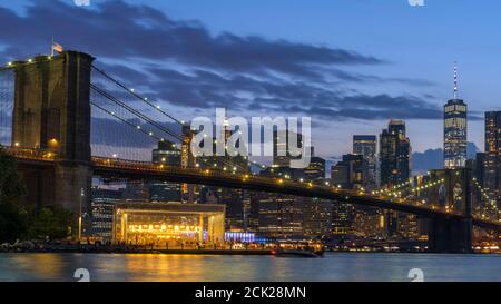 Brooklyn Bridge und Lower Manhattan bei Nacht beleuchtet. Blick vom Main Street Park. Stockfoto