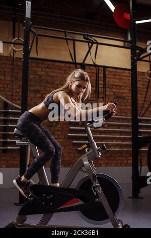 Nachdenklich junge Frau im Sport-Outfit sitzt auf der Heimtrainer nach dem erschöpften Training Stockfoto
