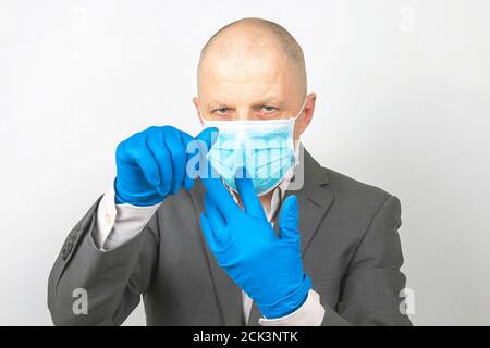 Geschäftsmann in einer medizinischen Maske zieht Schutzhandschuhe aus den Händen. Virus Quarantäne Stockfoto