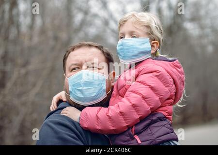 Kaukasischen Vater mit Kind Mädchen tragen sanitäre Gesichtsmasken im Freien. Familie Vater und Tochter schützen sich vor gefährlichen Ausbreitung des Virus. Stockfoto