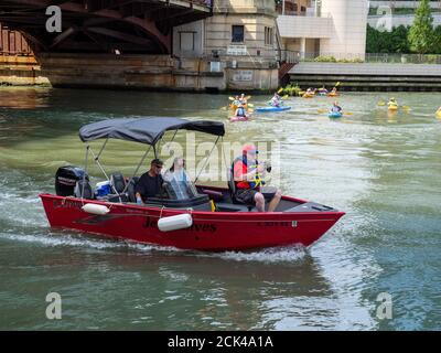 Kleines Ausflugsboot mit Fotograf auf dem Chicago River und Kajakfahrern. Stockfoto