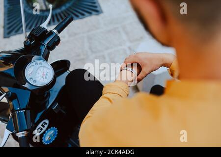 Ein Mann mit Bart sitzt auf einem kleinen Schwarzes Motorrad auf der Straße Stockfoto