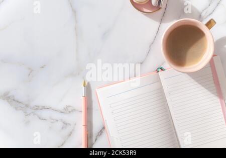 Minimaler Arbeitsbereich mit Tagebuch, Stift, Tasse Kaffee, Milch, französischem Macaron Stockfoto