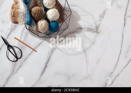 Verschiedene farbige Wollgarn Kugeln und gestrickten Winter Schal mit Häkelnadel im stylischen Netzkorb Stockfoto