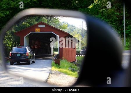 Die Ansicht der Fahrzeuge, die durch die Seidenstraße überdachte Brücke fahren Über Walloomsac River aus dem Rückspiegel eines Fahrzeugs.Bennington.Vermont.USA Stockfoto