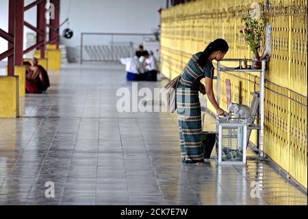 Eine Frau in der Chauk HTAT Gyi Pagode in Yangon, die ein Geld für eine buddhistische Gottheit anbietet. Myanmar (Birma) Stockfoto