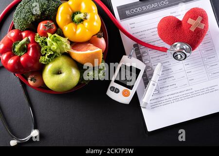 Welt Diabetes Tag und Gesundheitskonzept. Blutzuckerkontrolle des Patienten, diabetische Messung und gesunde Ernährung Essen Ernährung mit rotem Herz auf BL Stockfoto