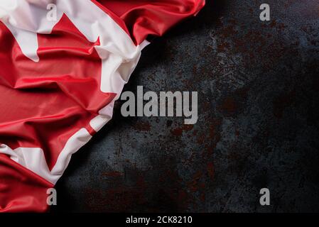 Nationalflagge von Kanada auf dunklem Steingrund, schön gefärbt mit Stofftextur und Kopierraum. Stockfoto