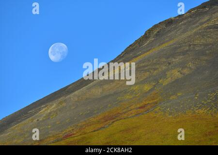 Der abnehmende Mond untergeht an einem Herbstmorgen in Seward, Alaska, hinter Mount Marathon. Der Berg ist der Schauplatz für den jährlichen Mount Marathon ra der Stadt Stockfoto