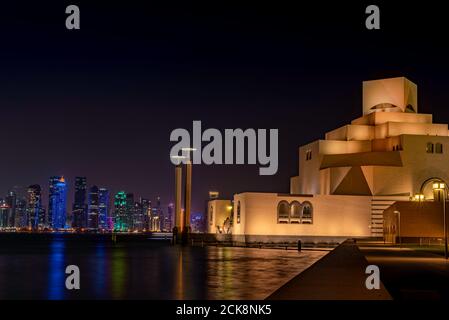 Doha, Katar - 26. August 2020: Das Museum für Islamische Kunst (MIA) Wahrzeichen Gebäude bei Nacht, mit Doha, Katar Skyline und Bucht Hafen als Hintergrund Stockfoto