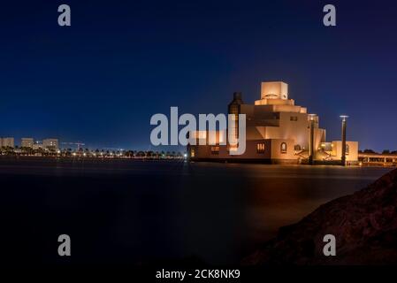 Doha, Katar - 26. August 2020: Moderne arabische Architektur des Museums für Islamische Kunst in Doha, Katar, mit nächtlicher Skyline im Hintergrund Stockfoto