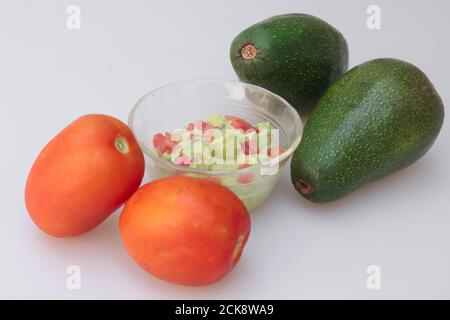 Nahaufnahme von Guacamole Sauce in einem Glas mit Ganze Avocados und Tomaten Stockfoto
