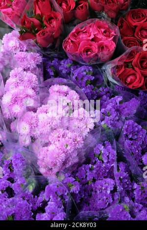 Frische blühende Blumen in einem lokalen Blumengeschäft in einem täglichen Markt, schöne rosa Nelken, rote Rosen und lila Statice Bündel. Draufsicht. Stockfoto