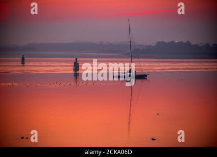 Wismar, Deutschland. September 2020. Im rötlichen Morgenlicht in der Wismarer Bucht liegt ein Segelboot vor Anker. Quelle: Jens Büttner/dpa-Zentralbild/dpa/Alamy Live News Stockfoto