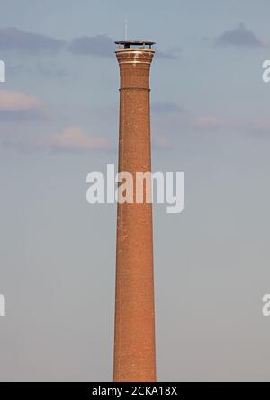 Isolierter alter verwitterter hoher Industrieschornstein, rot Stockfoto