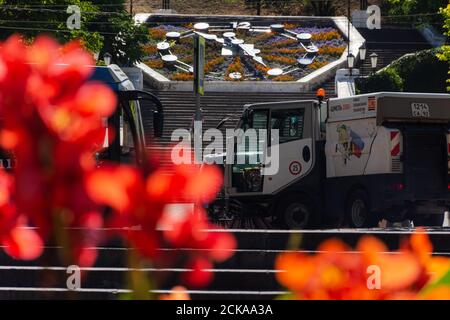 Sewastopol Stadtzentrum mit Menschen und Autos am 13. August 2020. Reinigung der Straße mit einem kleinen Hummel Auto. Bunte Stadtlandschaft. Rote Kannas in A Stockfoto