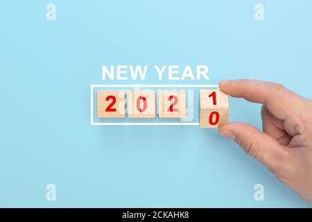 Man Hand Flipping Würfel mit Jahr 2020 bis 2021. Handwechsel Holzwürfel mit Neujahrs 2020 bis 2021 Konzept. Blauer Pastellhintergrund Stockfoto