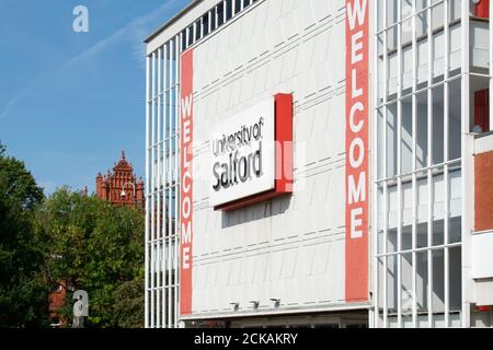 Eingang der Salford University mit Willkommensbanner. Schälen Sie das Gebäude im Hintergrund hinter Bäumen. Greater Manchester, Großbritannien. Stockfoto