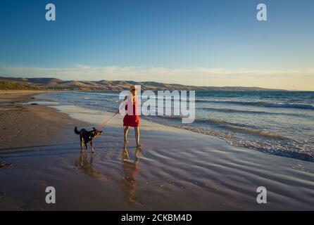 Schöne reife Frau und Hund aus Leine zu Fuß entlang der Küste am abgelegenen leeren Strand. Gesellschaft Vorteile der Tiere halten aktiv Rentner Stockfoto